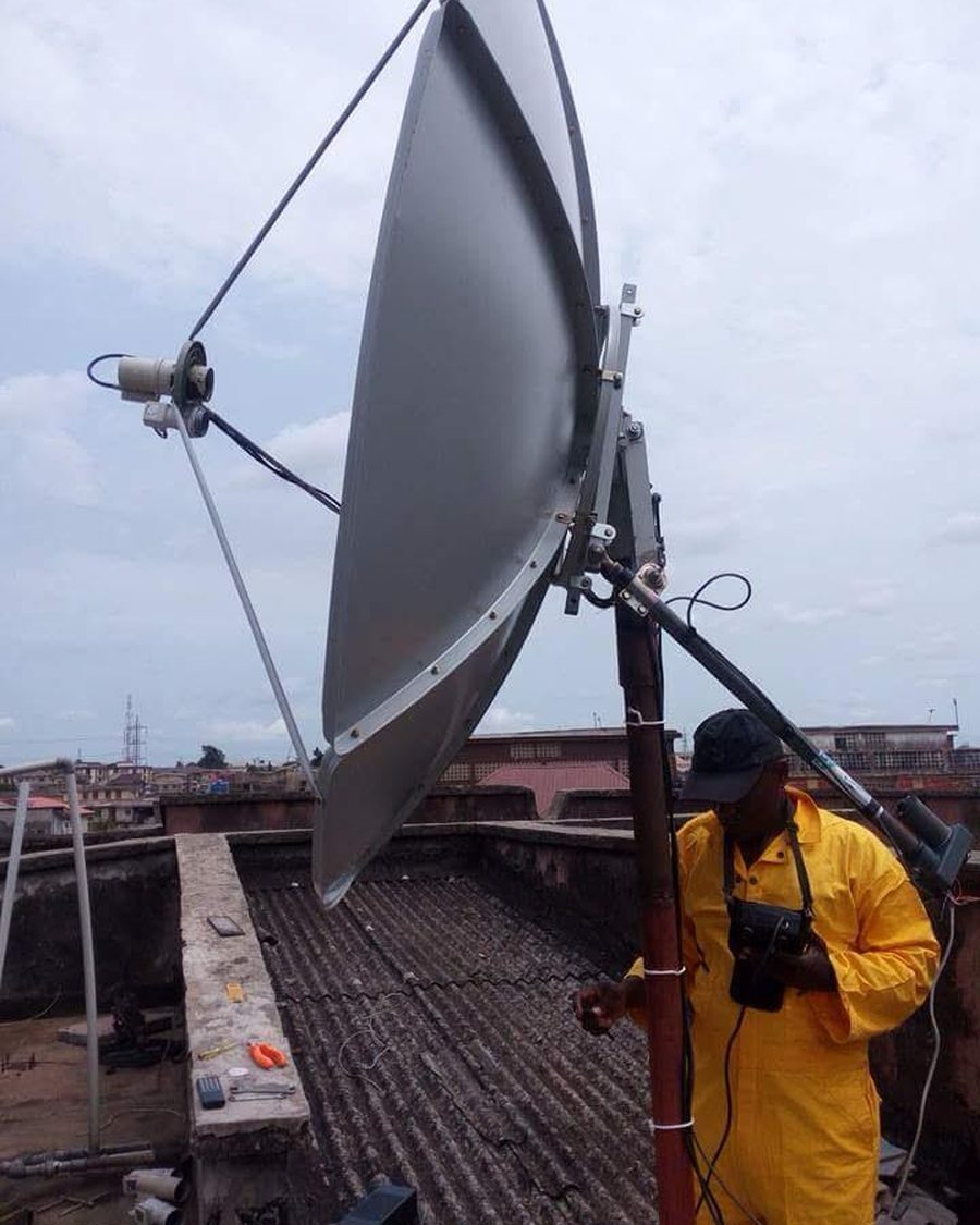 Close-up of a satellite dish mount being aligned with a signal meter on a roof.